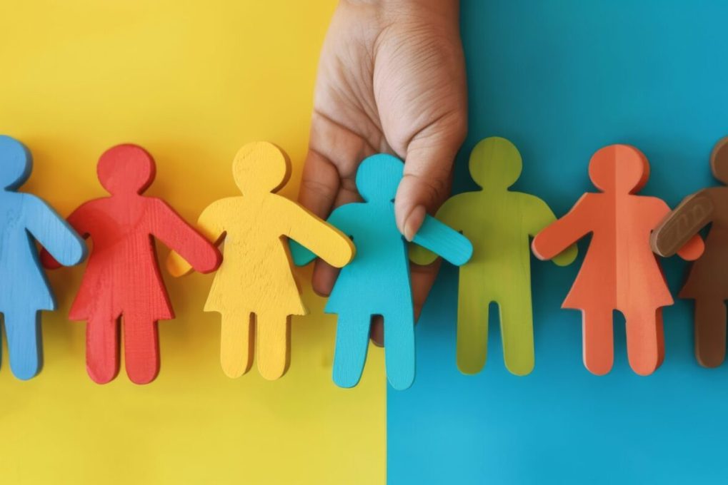 A hand holding a blue figurine placing it in a row of colorful figurines. A hand holding a blue figurine placing it in a row of colorful figurines.
